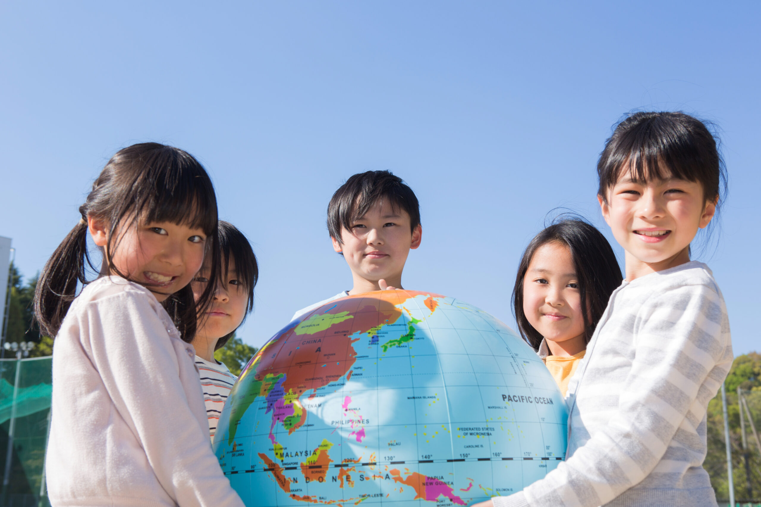 子供達が両手で地球儀を支えている。